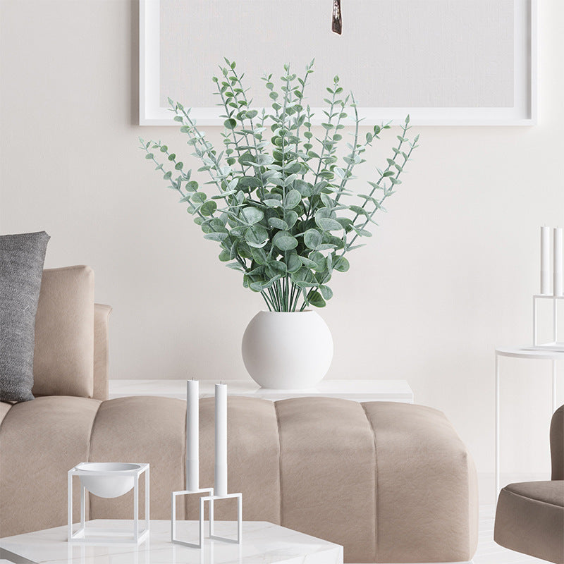 Faux eucalyptus arranged in a white vase