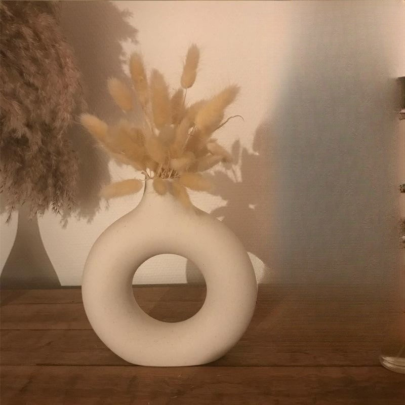 White ceramic donut vase with dried grasses in warm light